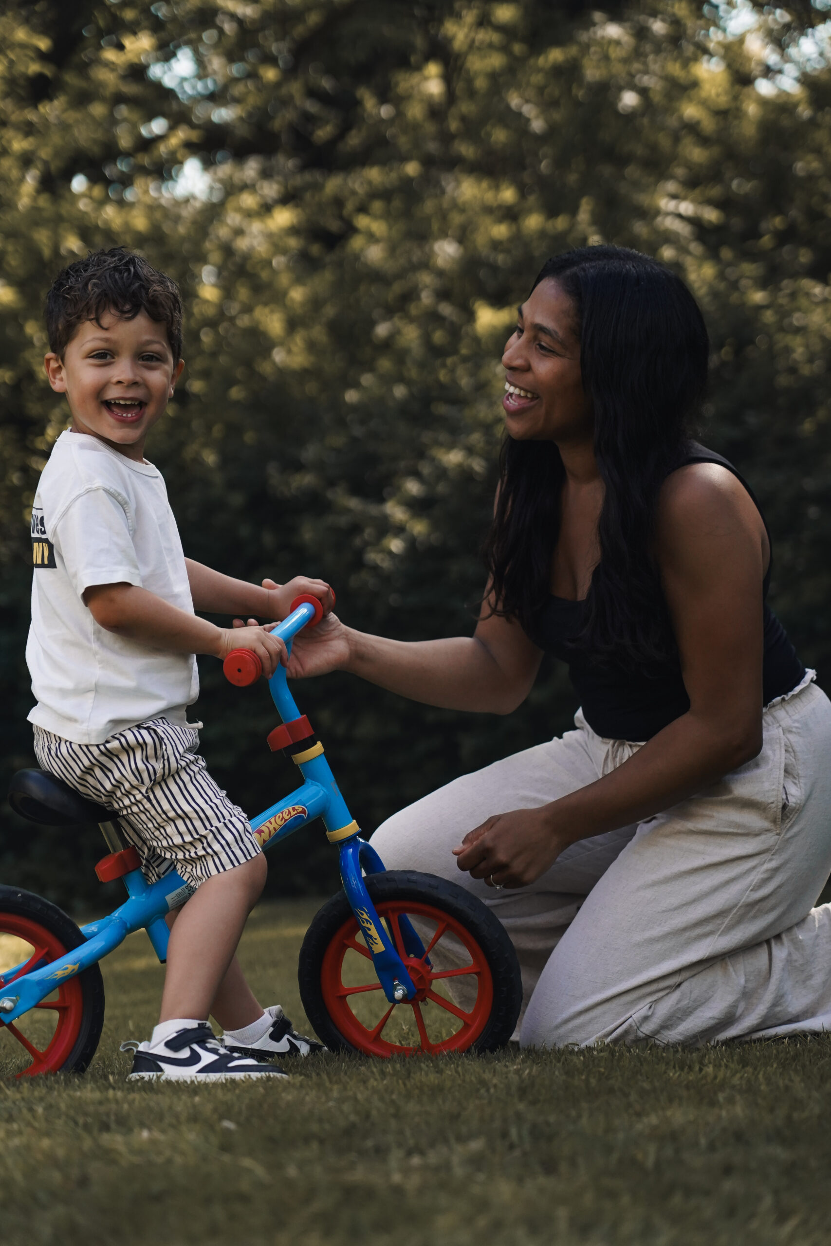 Mother helping her son ride a balance bike outdoors during a family photography session