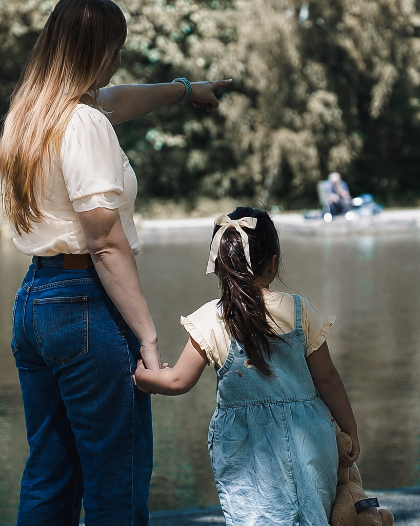 Mother and daughter looking out over a lake together during a family photoshoot