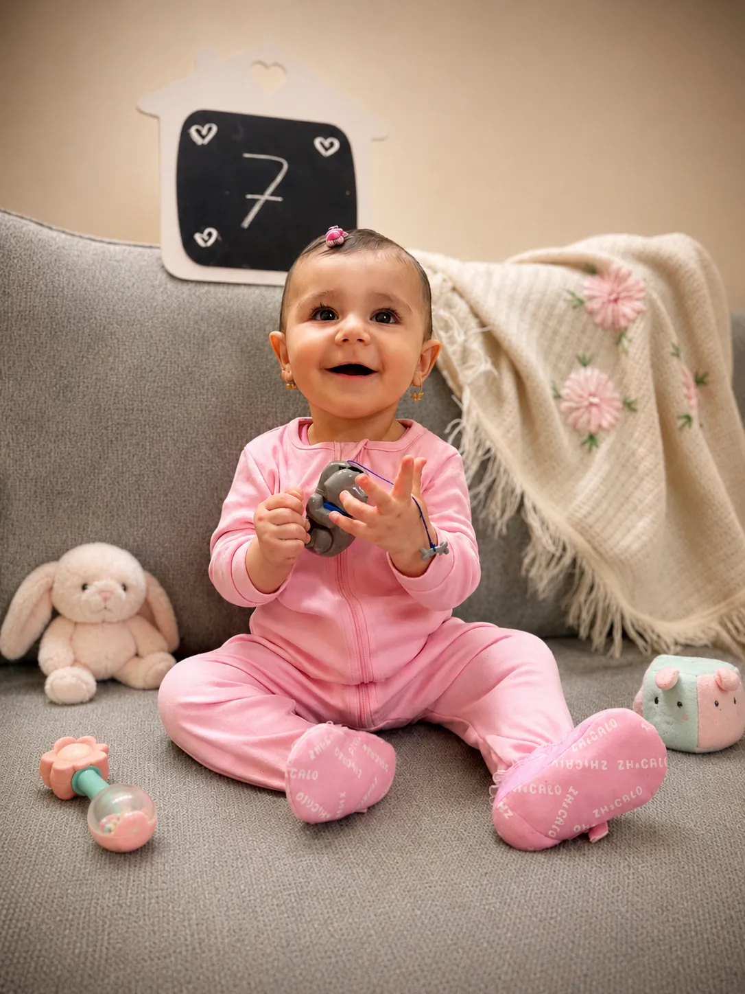Smiling baby girl sitting among toys during a seven month milestone photography session