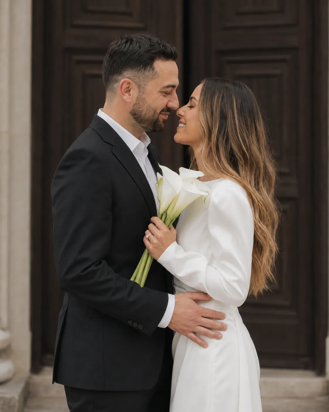 Bride and groom sharing a close embrace outside a courthouse entrance