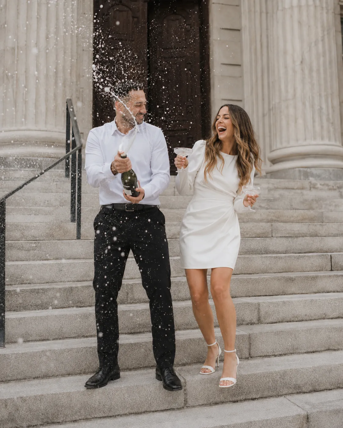 Bride and groom celebrating with champagne on the courthouse steps