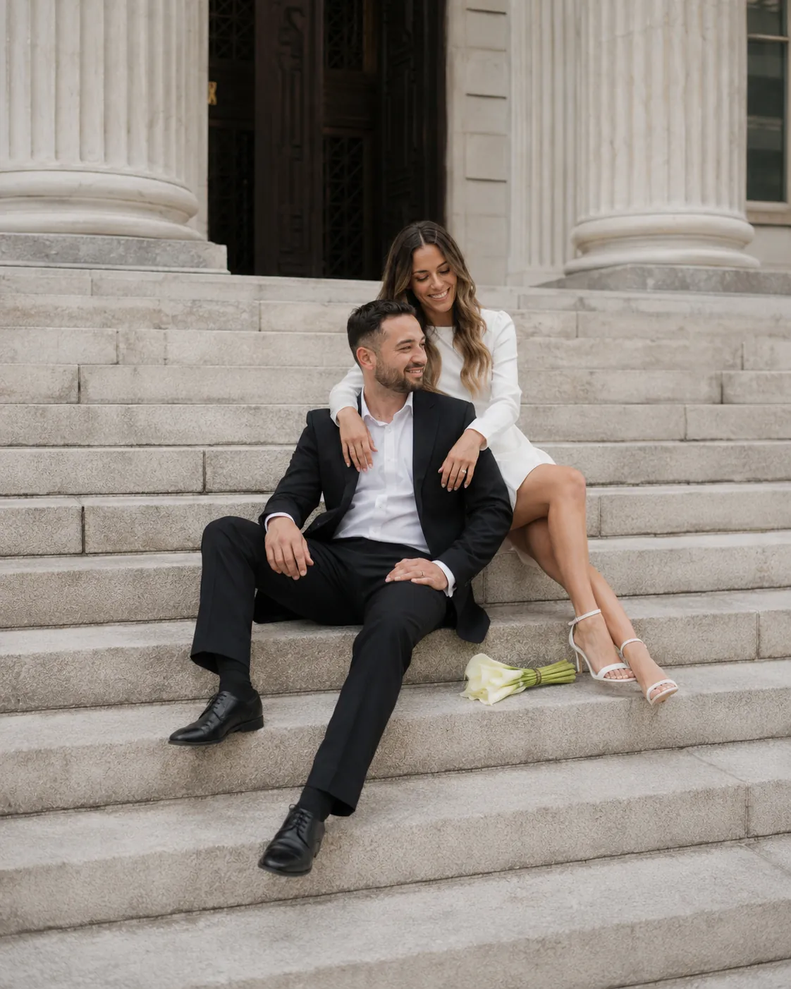 Bride and groom sitting together on courthouse steps after their ceremony