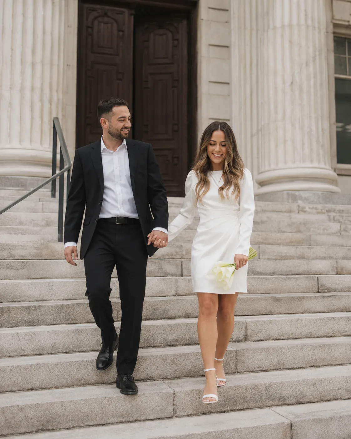Bride and groom walking hand in hand down courthouse steps