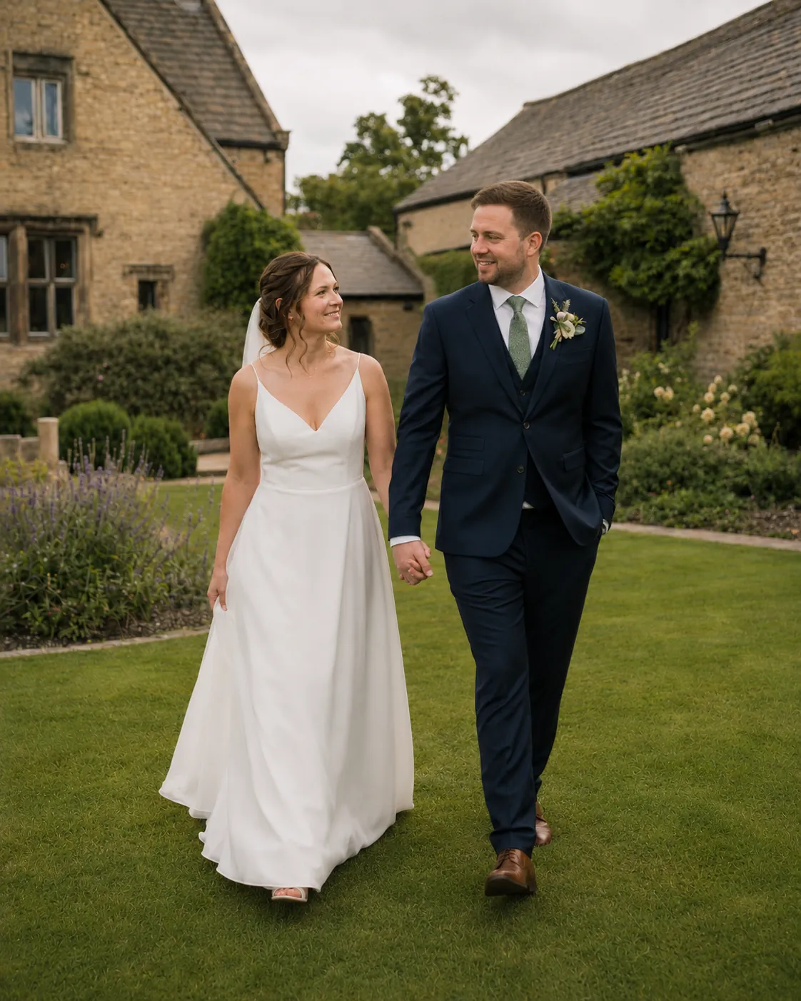 Bride and groom walking hand in hand through the grounds of a stone wedding venue