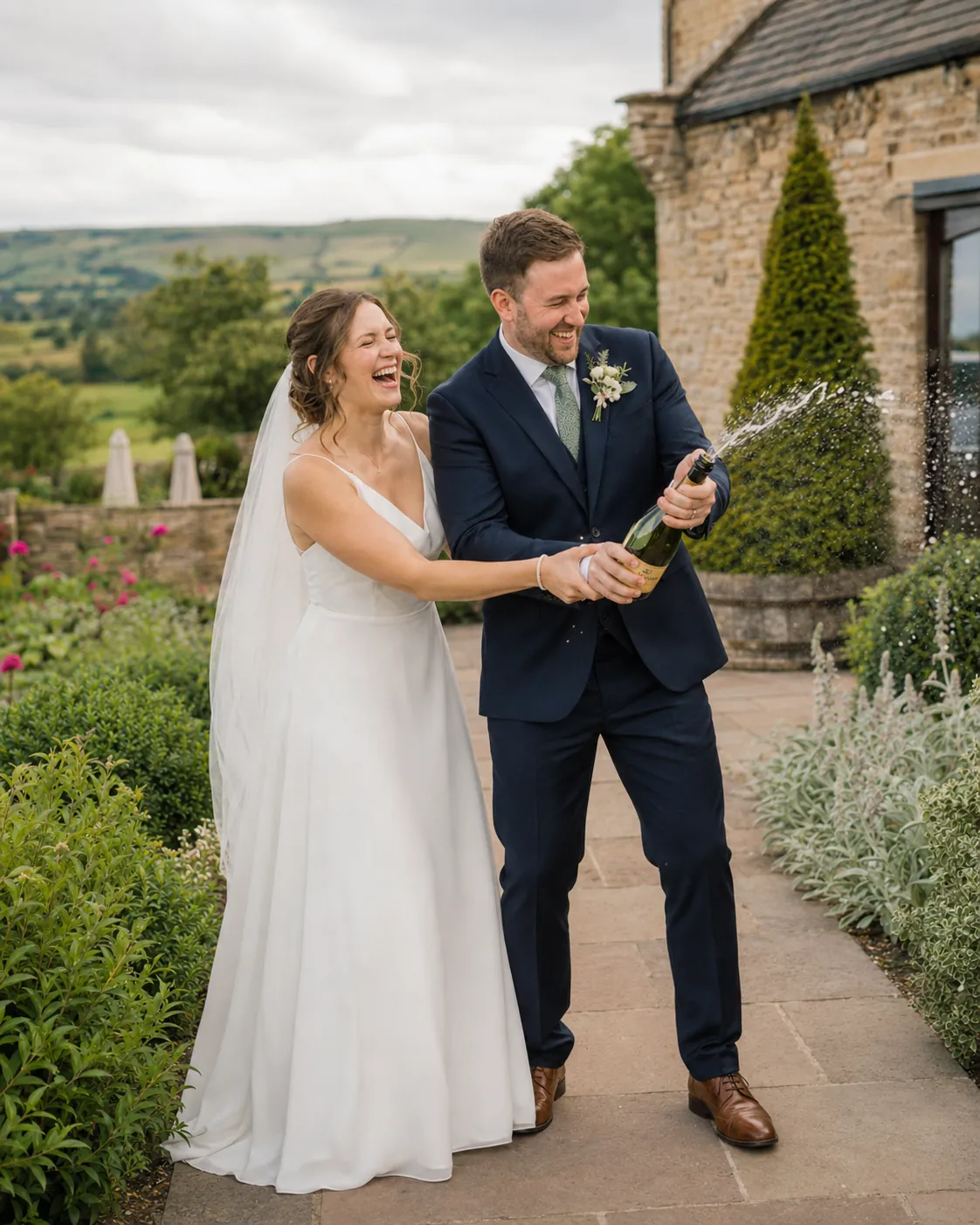 Bride and groom laughing while popping champagne outdoors