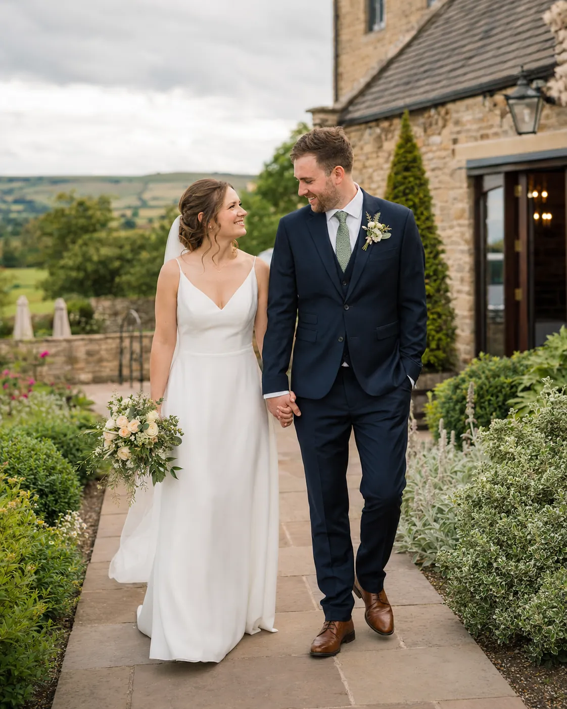 Bride and groom walking together outside a Yorkshire stone wedding venue