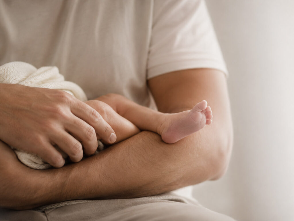 Close-up of a newborn baby's foot cradled in a parent's arms